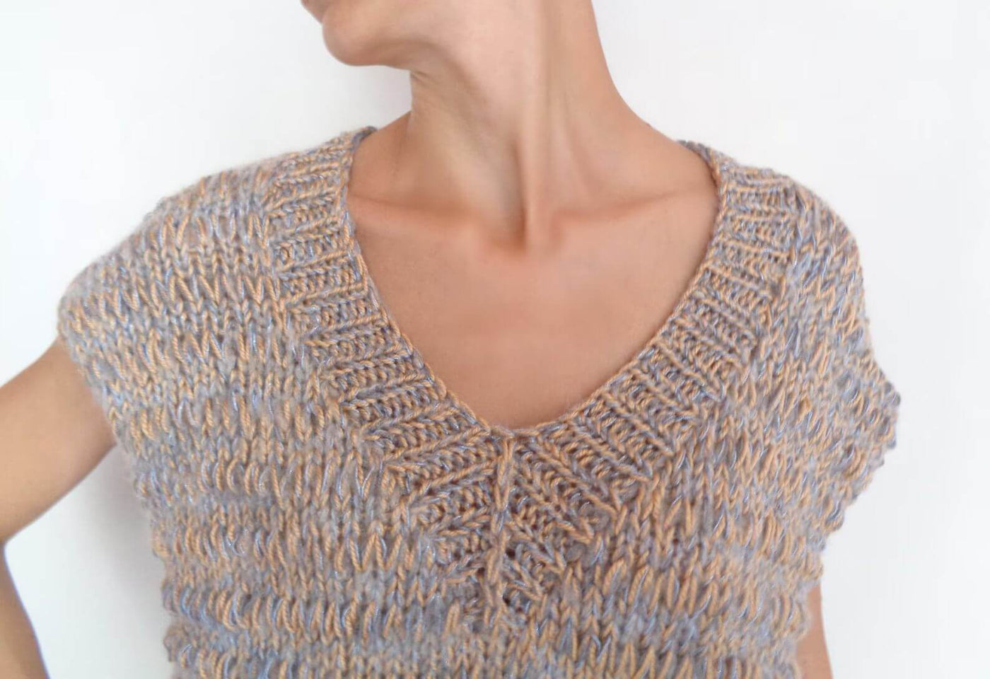 Close-up of a woman wearing a multicolor alpaca blend sweater vest with a V neck and short sleeves.