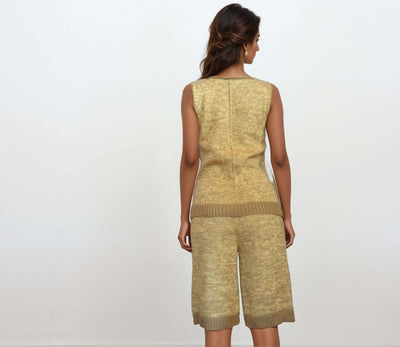 Back view of a woman in a beige knit set co-ord featuring a V-neck top and matching shorts.