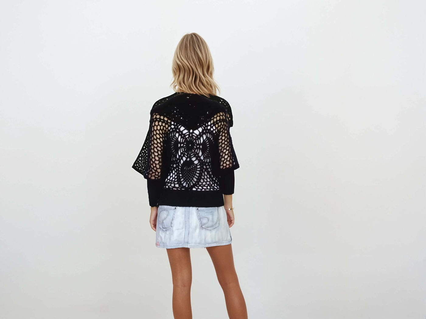 Back view of a black lace hooded crochet bomber jacket featuring a pineapple pattern, worn over a skirt.