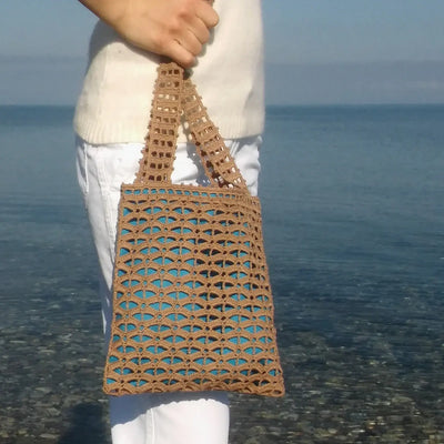 Small handmade brown crochet tote bag with geometric mesh pattern and blue lining, featuring short handles for comfort.