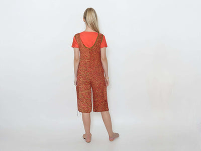 Back view of a woman in a knitted short jumpsuit romper with pockets, featuring a vibrant color gradient blend.