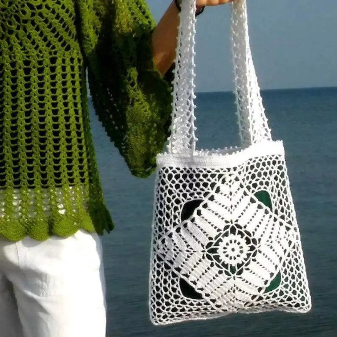 White crochet tote bag with elegant openwork lace pattern and green linen lining, held by a person, perfect for casual outings.