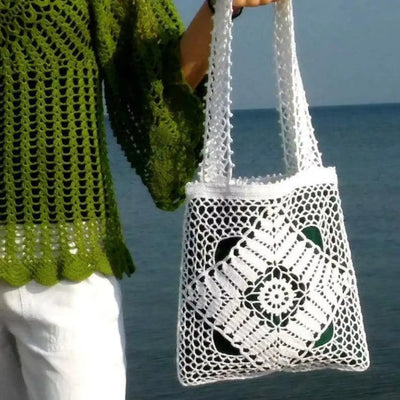 White crochet tote bag with elegant openwork lace pattern and green linen lining, held by a person, perfect for casual outings.